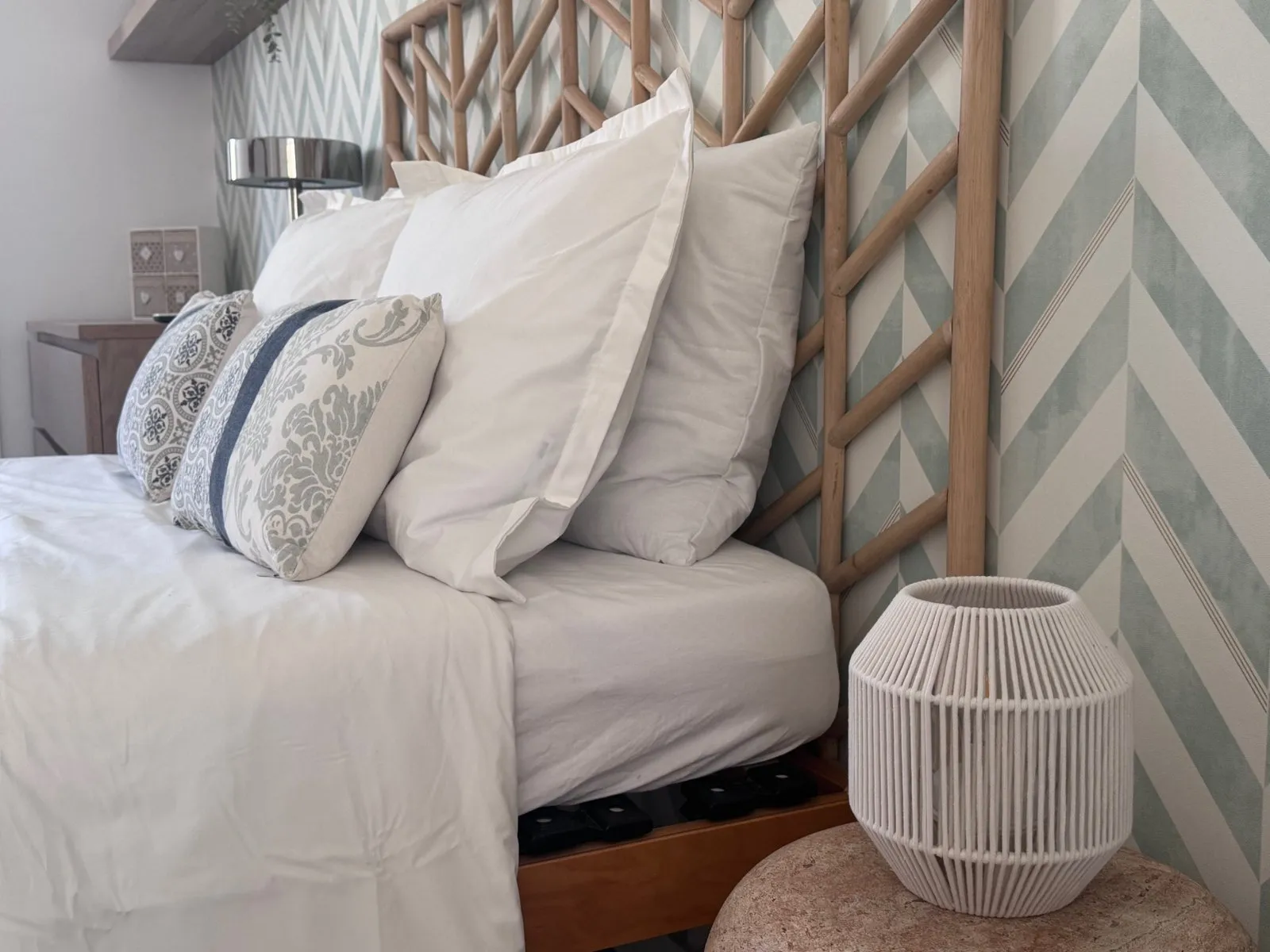 Quarto da Almoura com cabeceira de bambu, papel de parede em verde-água e candeeiro de corda