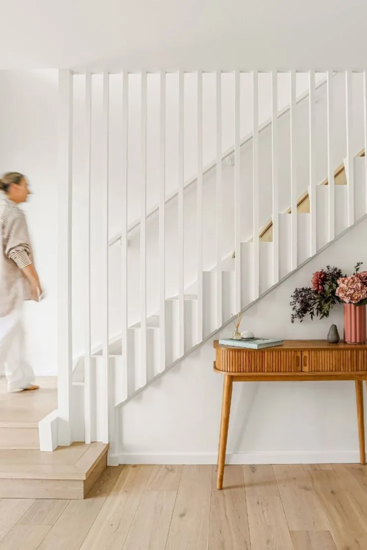 Escada branca com degraus de madeira numa casa renovada